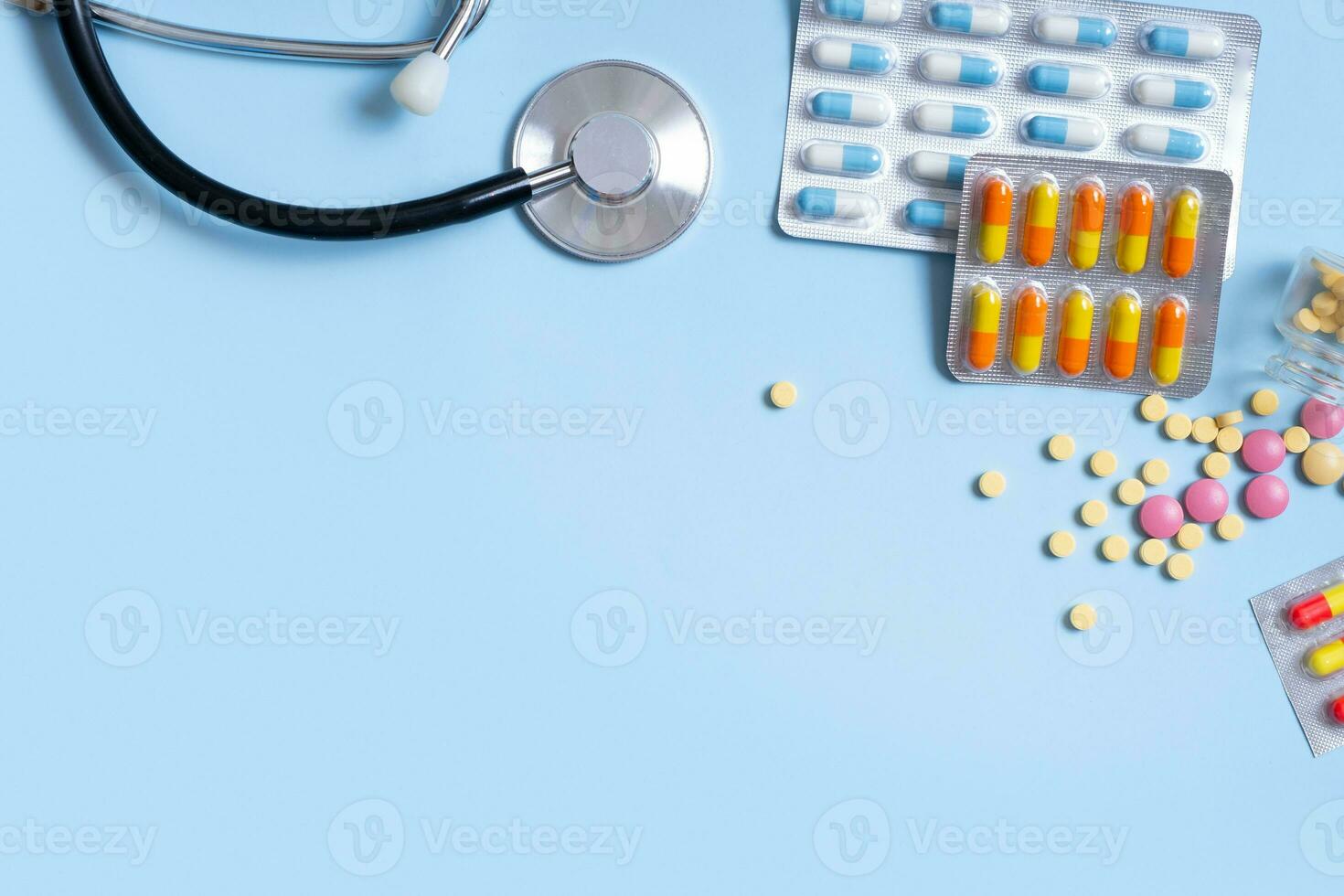 Colorful pills, stethoscope on blue background with copy space. Healthcare and medicine background flat lay photo