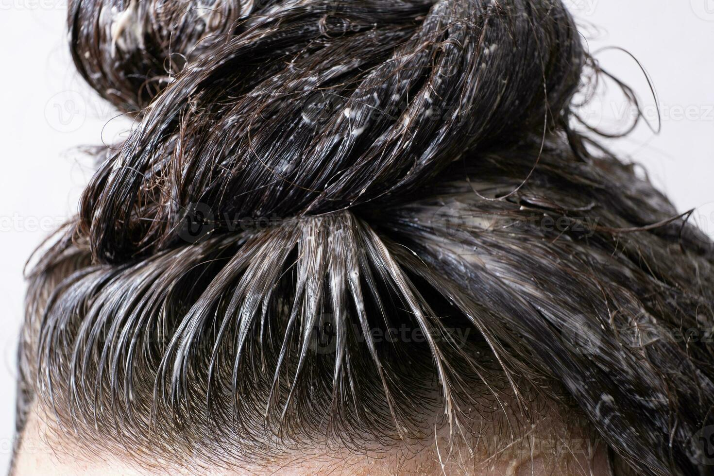 Close up women's hair is collected in a bun with paint applied to it. Hair dyeing concept photo