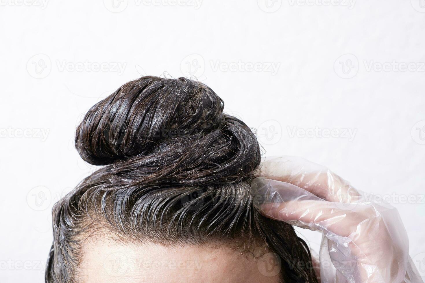 Women's hair is collected in a bun with paint applied to it. Hair dyeing concept photo