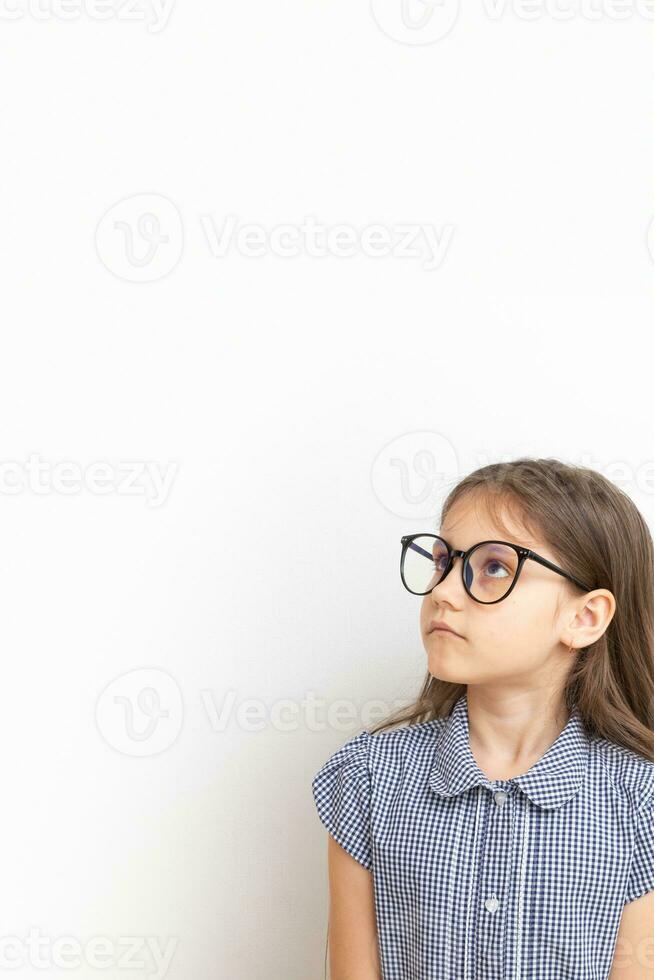 A 7-year-old girl with glasses with sad faces. Children's education, learning concept with copy space. Vertical format photo