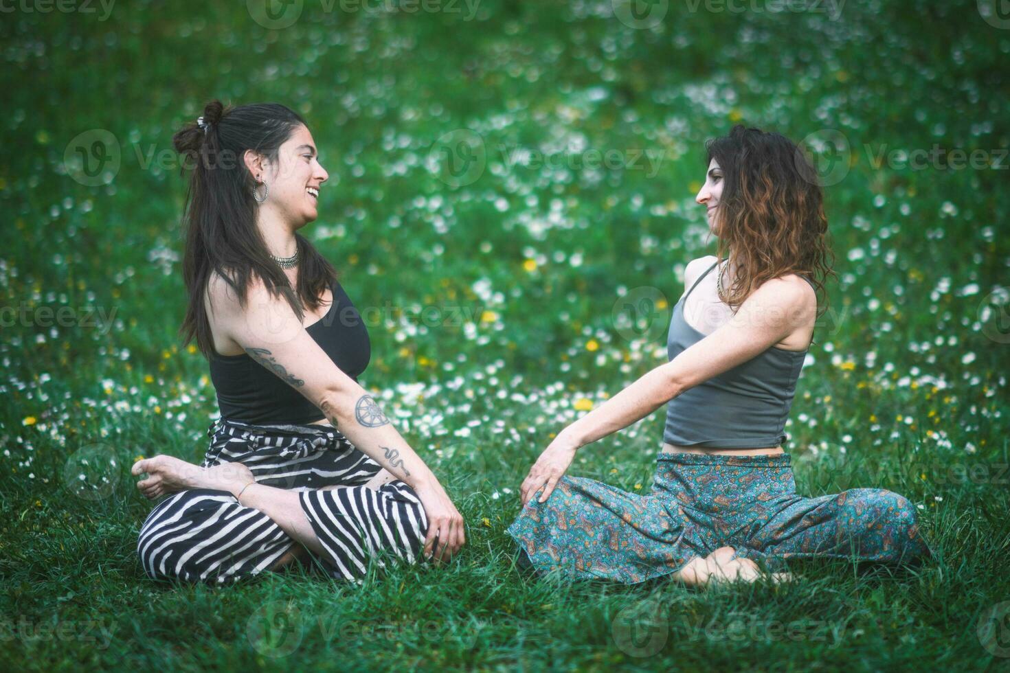 Couple of young women look at each other during a yoga session photo