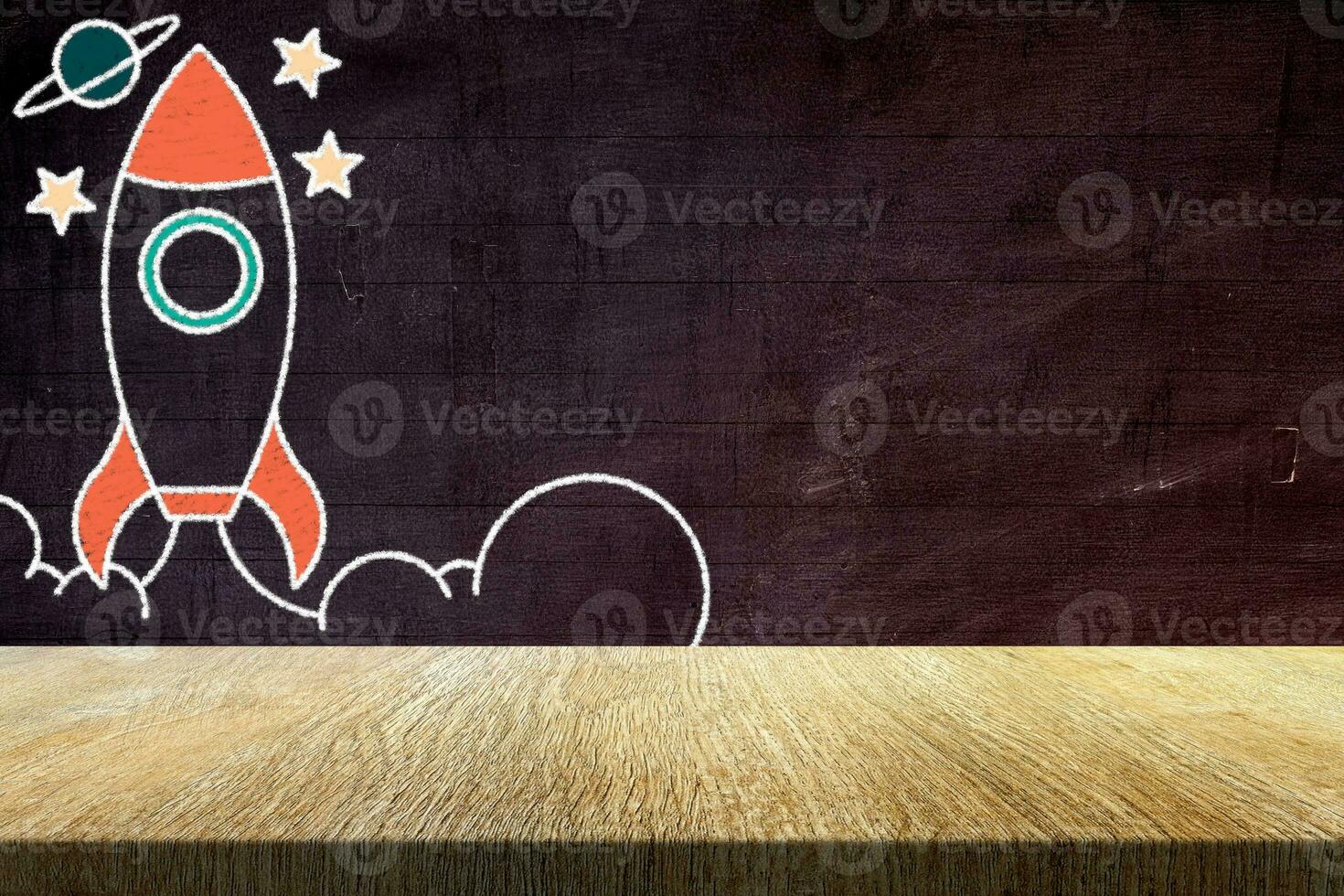 Wood Table with Retro Rocket in Chalk Drawing Style on Grunge Chalkboard Background, Suitable for Product Presentation Backdrop, Display, and Mock up in Back to School, Start up and Education Concept. photo