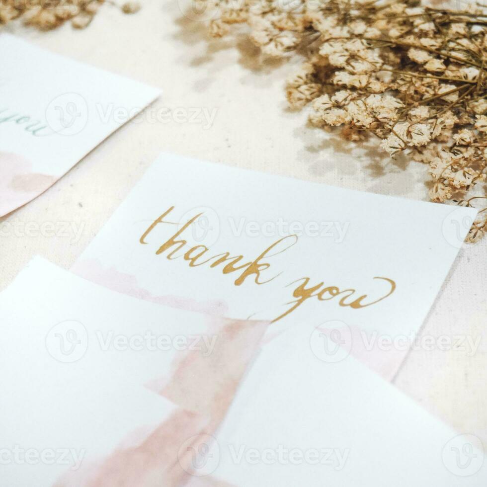 A white card with gold lettering that says thank you on it. photo