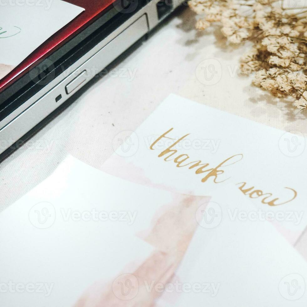 A white card with gold lettering that says thank you on it. photo