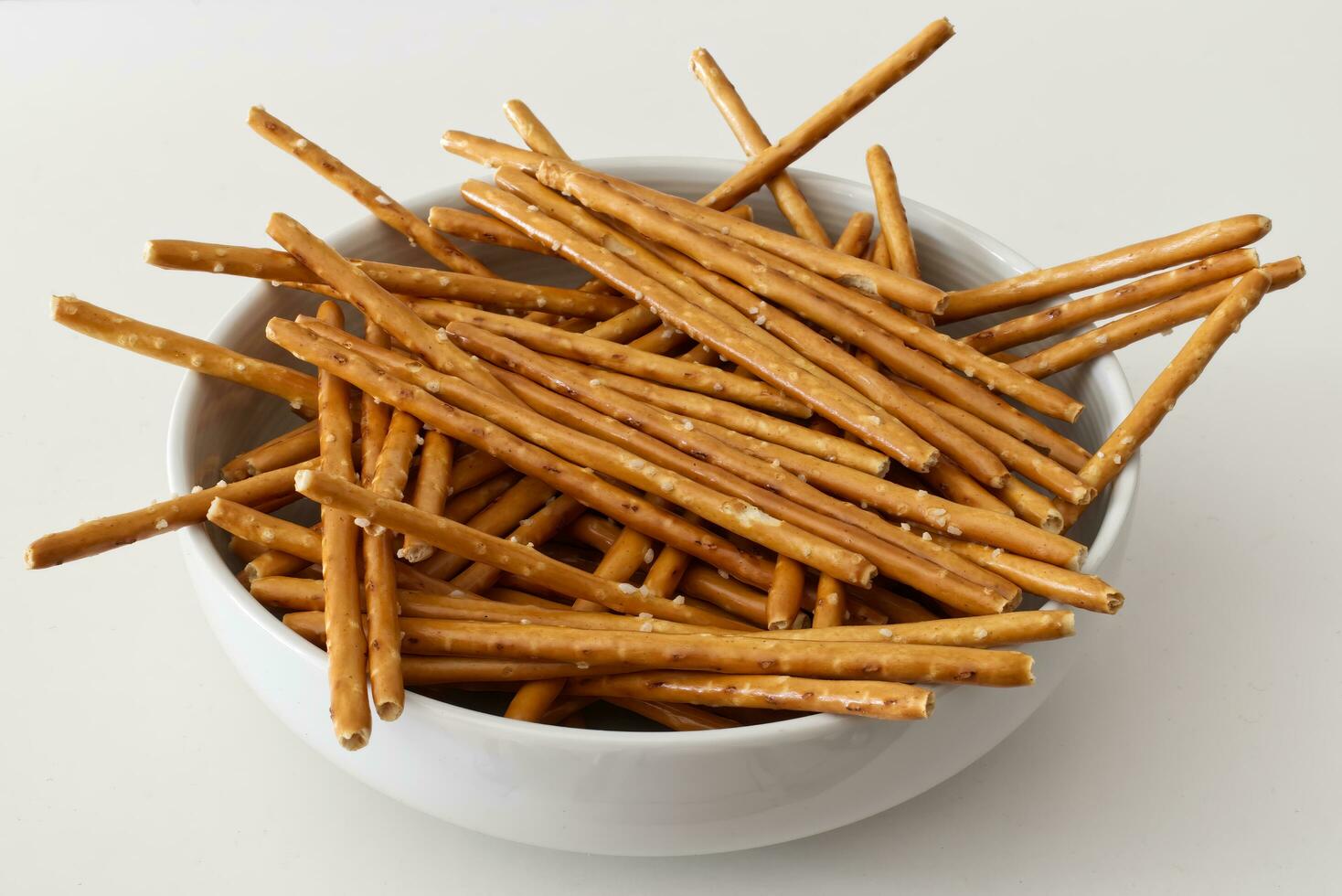 Salted pretzel sticks in a bowl isolated on white background photo