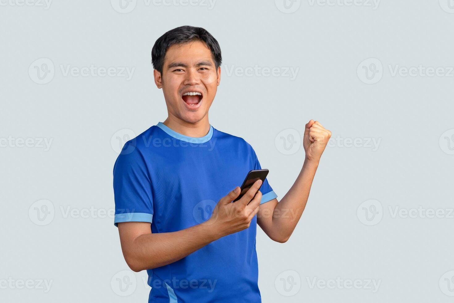 Happy man cheering excitedly in celebration after good news. Excited guy winner holding cellphone winning game online or investing trading, using mobile app celebrates victory success photo