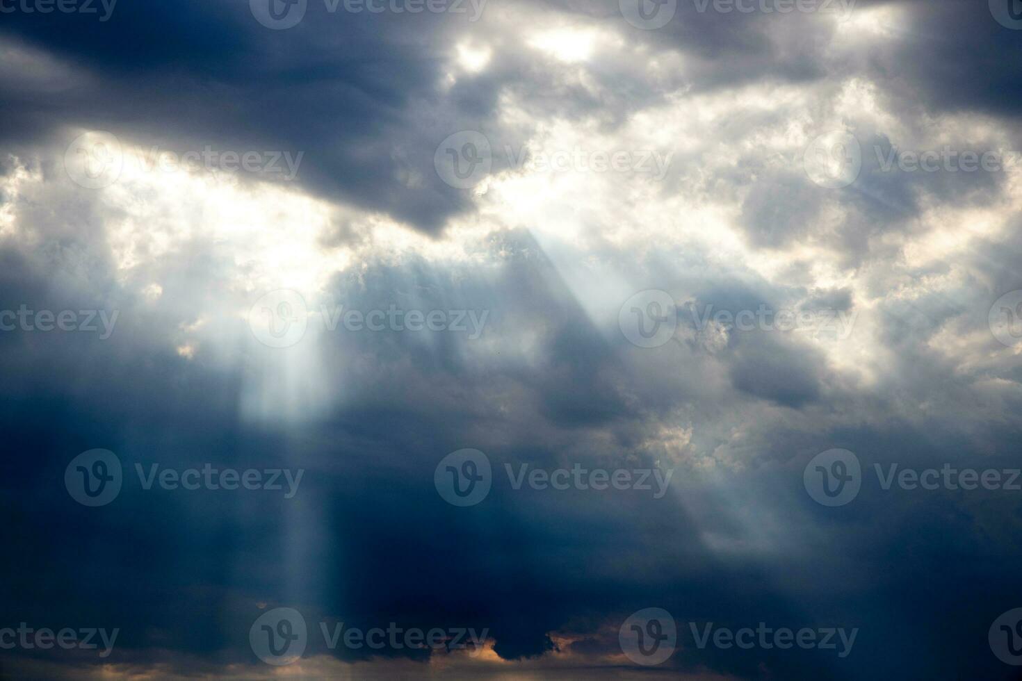 threatening dramatic sky with dark clouds and rays of summer sun photo