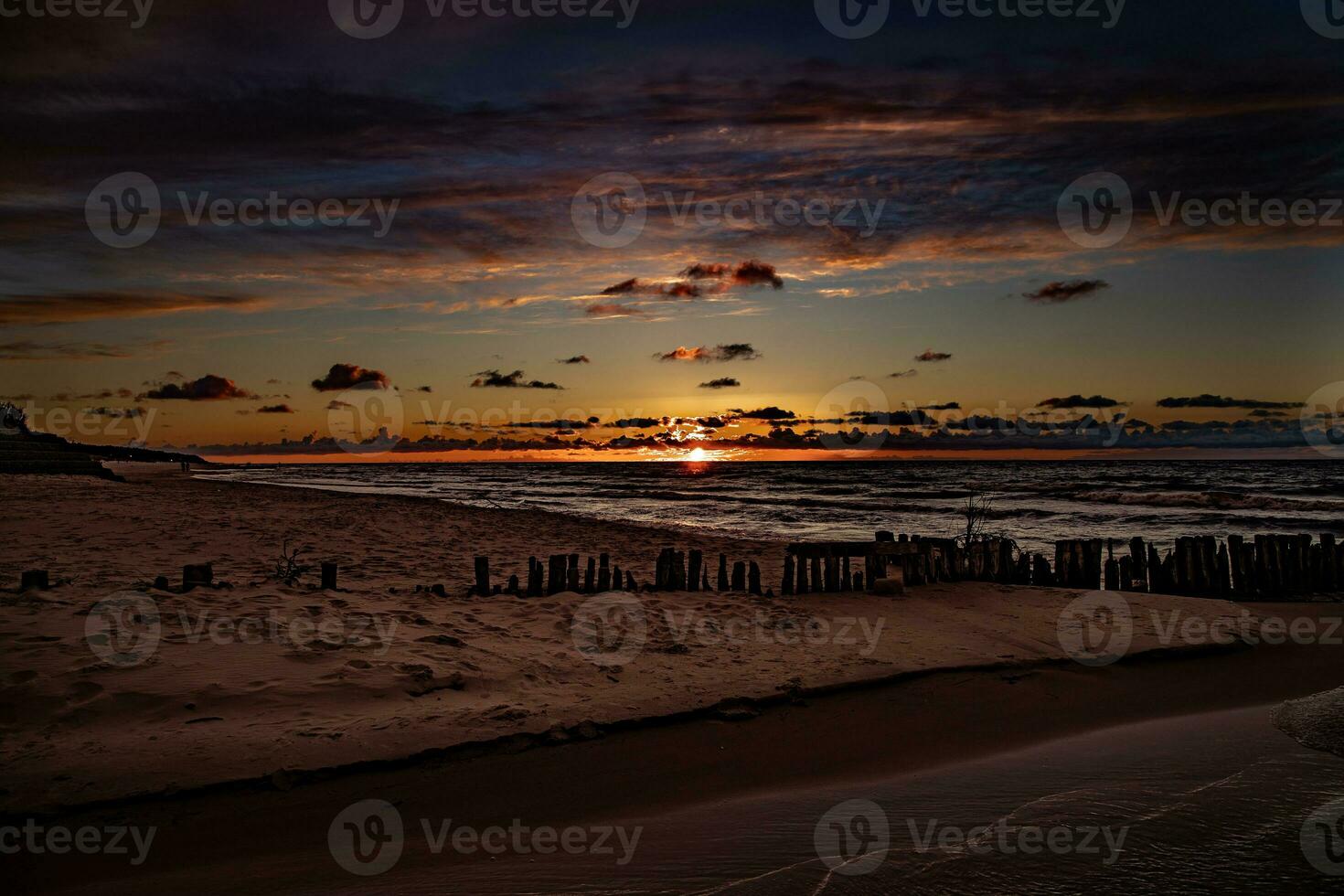 vistoso puesta de sol terminado el polaco báltico mar con oscuro cielo nubes y rompeolas foto