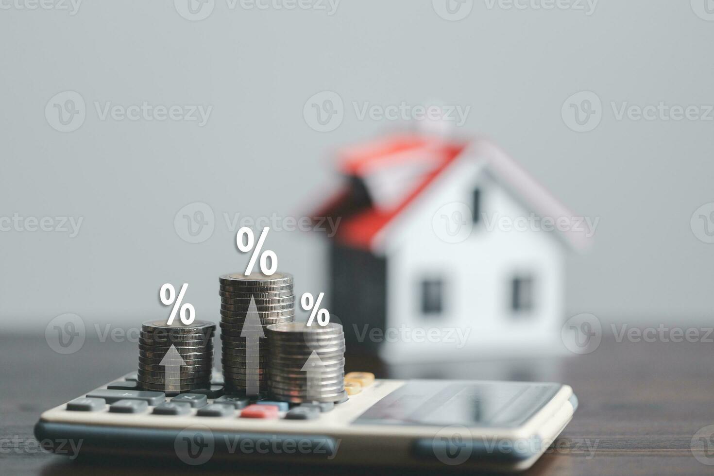 Stacks of coins and model house with percentage symbol for increasing interest rates. Interest rate financial and mortgage rates. Icon percentage symbol and arrow pointing up. Home price or increase. photo