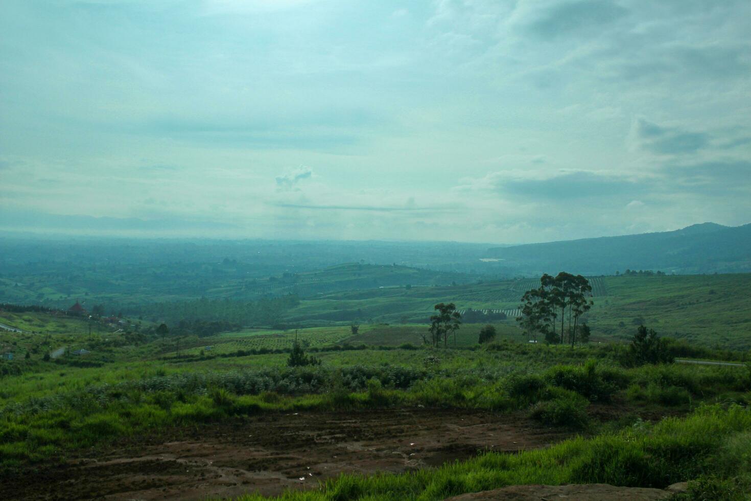 aerial view with beautiful green hills landscape.  a meadow with a cloud shadow and a distant layer of mountains in the air mist photo