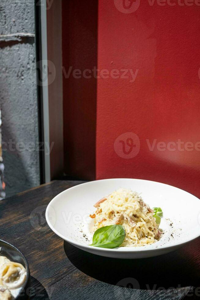 italiano pasta en negro café mostrador siguiente a el ventana, teniendo almuerzo foto