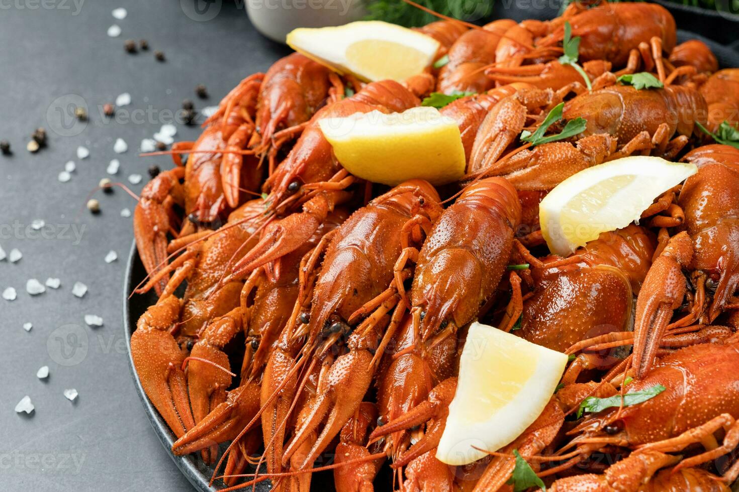 top view of cooked crawfish platter with lemons and spices on cement background photo