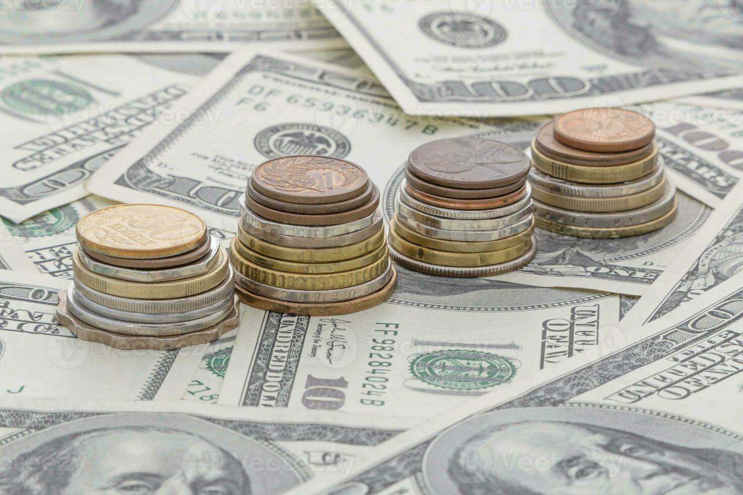 piles of coins standing on one hundred US dollars banknotes photo