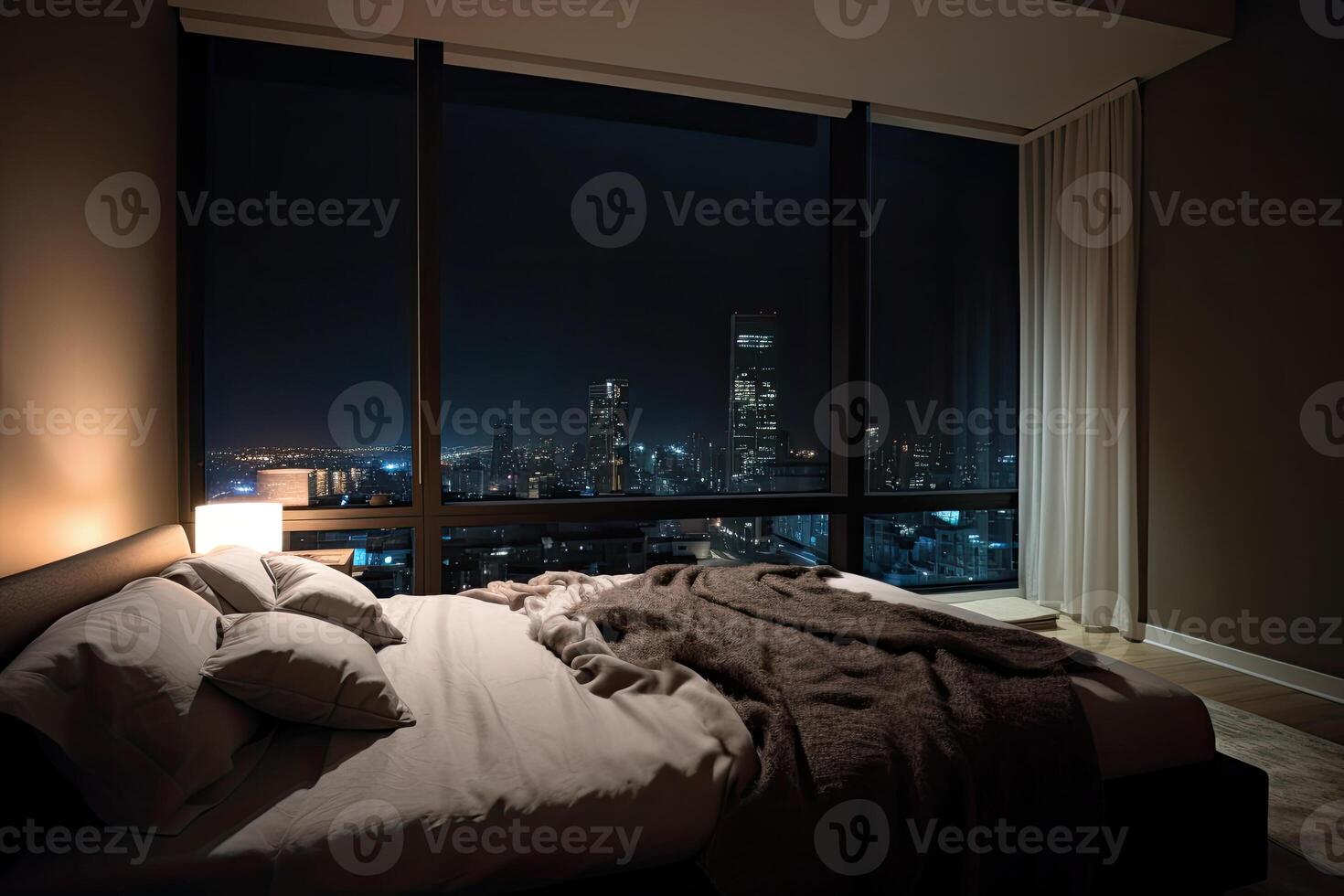 Large bed in living room with night city view in window. photo