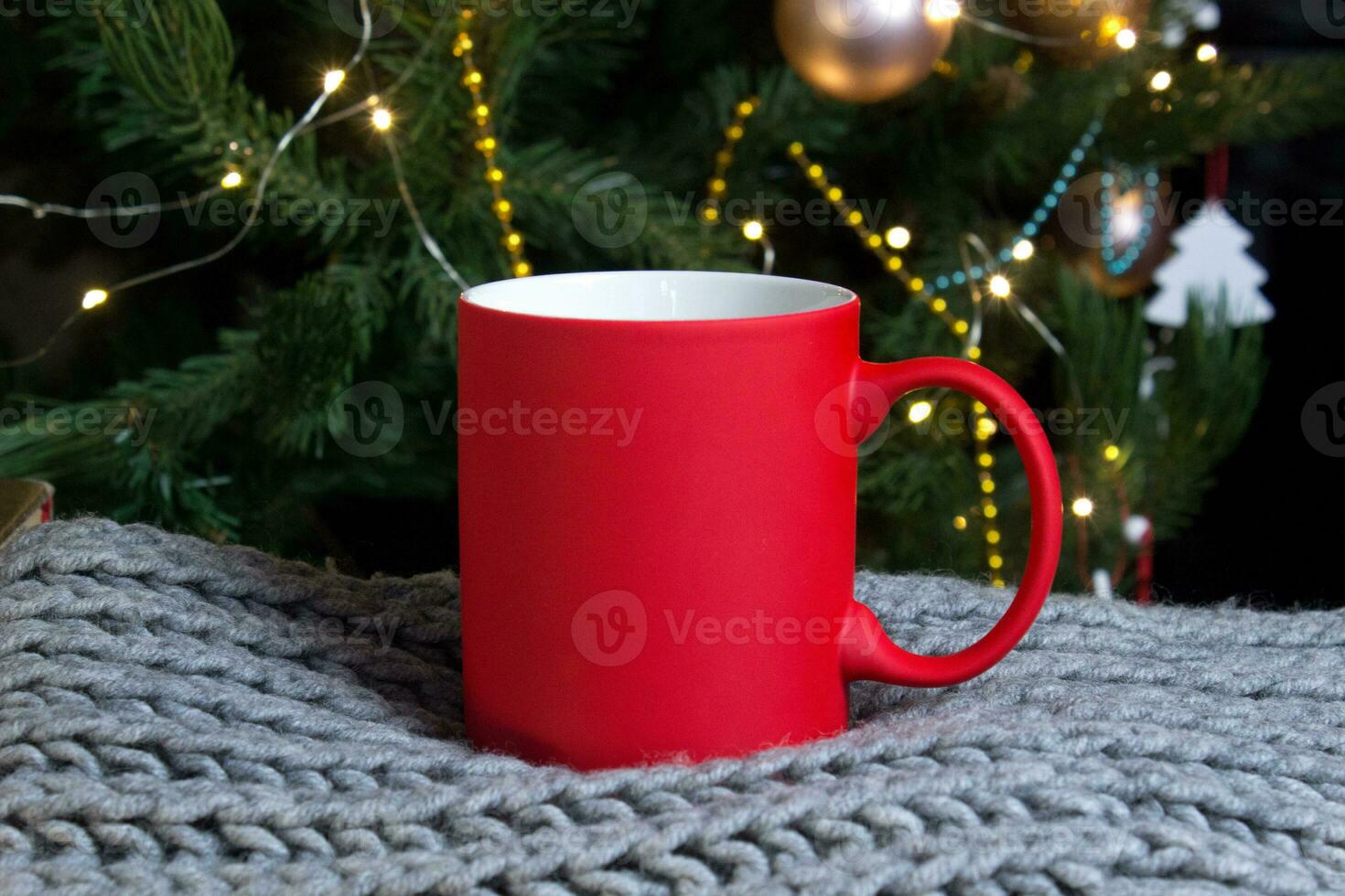 Blank red mug with christmas tree on background,mat tea or coffee cup with christmas and new year decoration,vertical mock up with ceramic mug for hot drinks,empty gift print template. photo