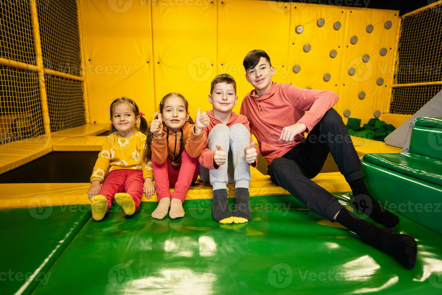 Four kids together sit at playground park. Sisters and brothers in active entertaiments. photo