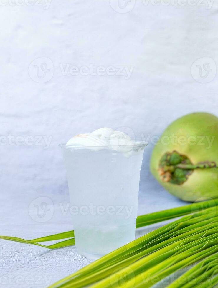 bebida de agua de coco helada en un vaso de plástico y coco sobre fondo blanco foto