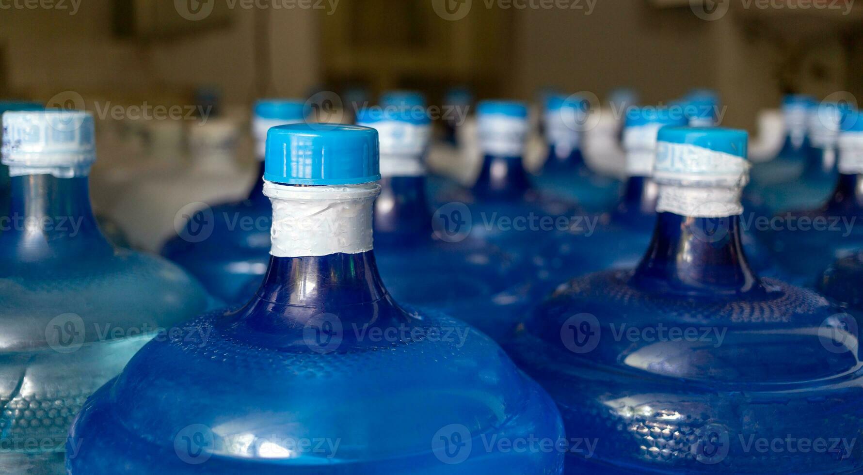 el galón de agua azul que contiene agua potable ha sido sellado con un sello de plástico en la planta de agua potable para esperar la entrega foto