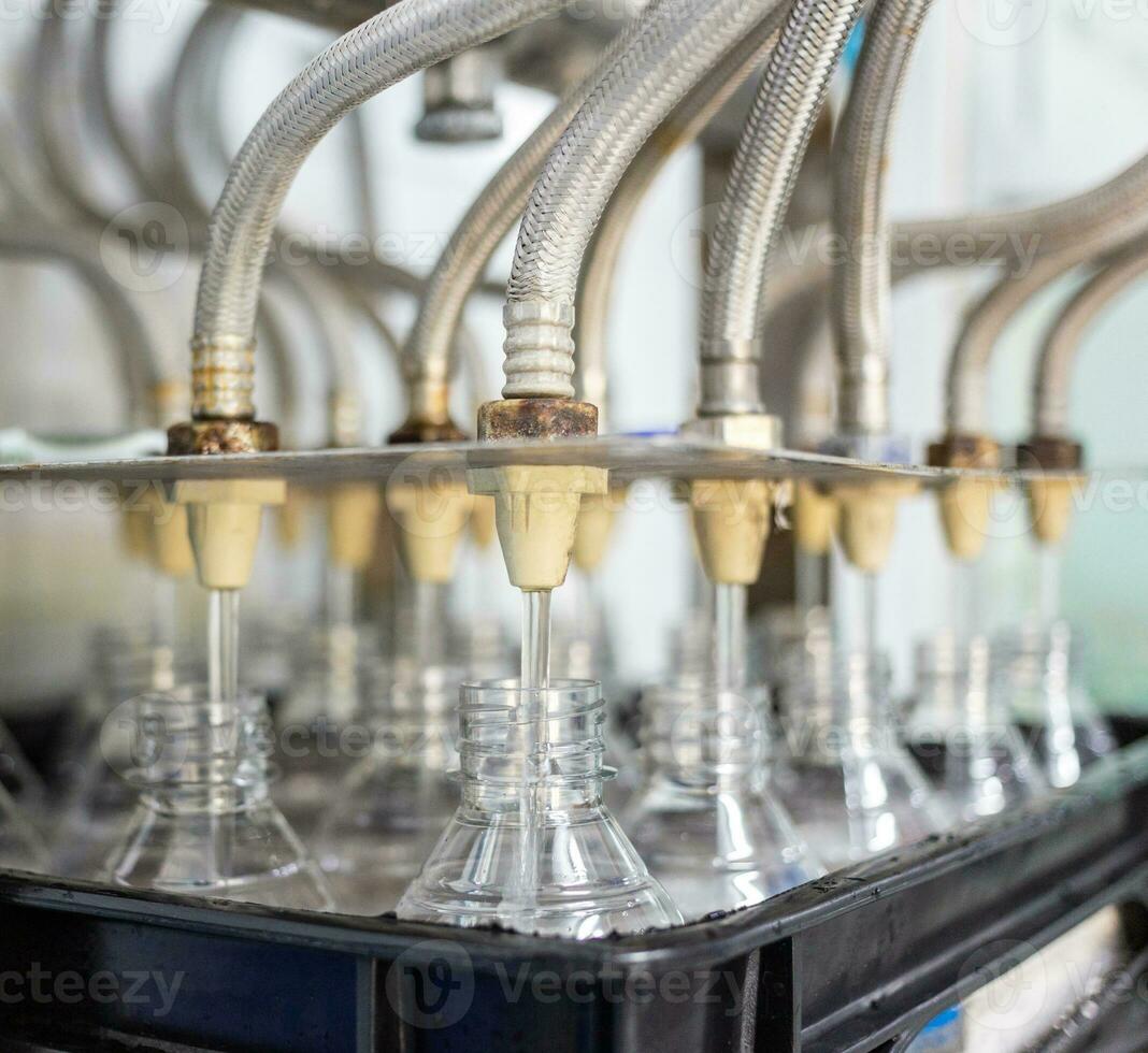 Bottling plant-Water bottling line for processing and bottling drink water into bottles. Bottle filling with drink water poured in a clear plastic bottle photo