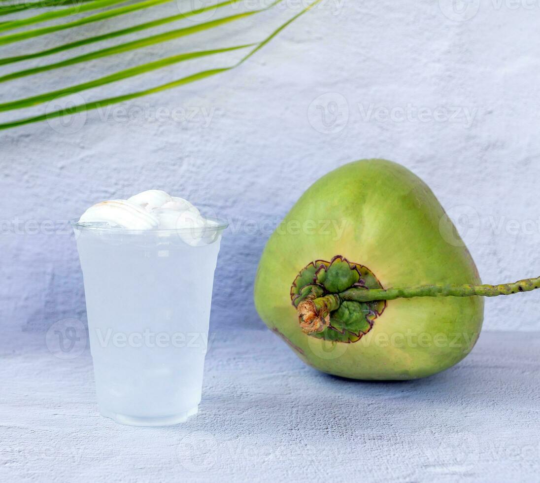 bebida de agua de coco helada en un vaso de plástico y coco sobre fondo blanco foto