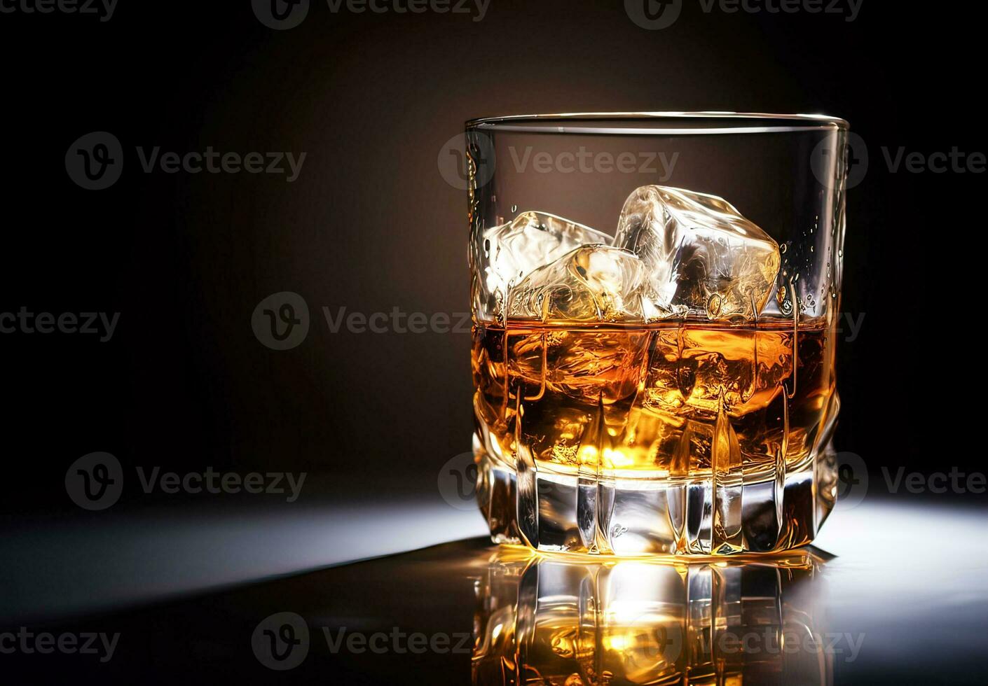 Whiskey with ice in glass on black background photo