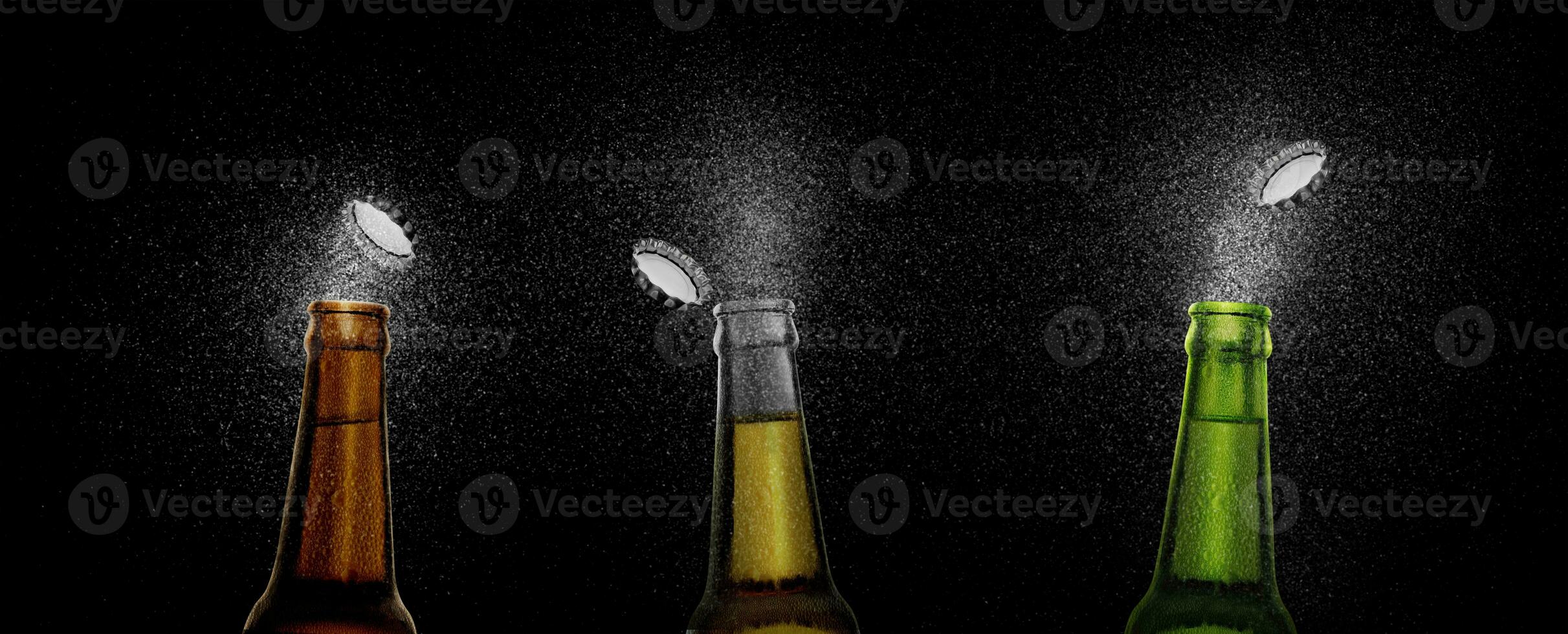 Closeup photo of an three beer bottle splashing beer drops on a black background. Beer cap flying on top of the bottle