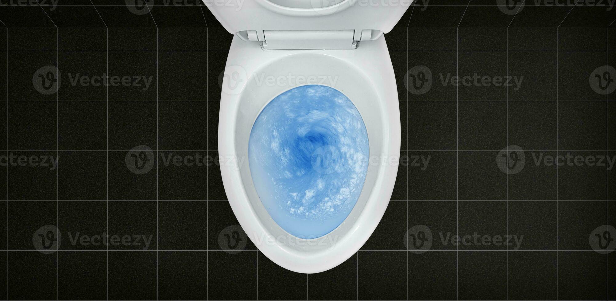 Top view of toilet bowl, blue detergent flushing in it photo