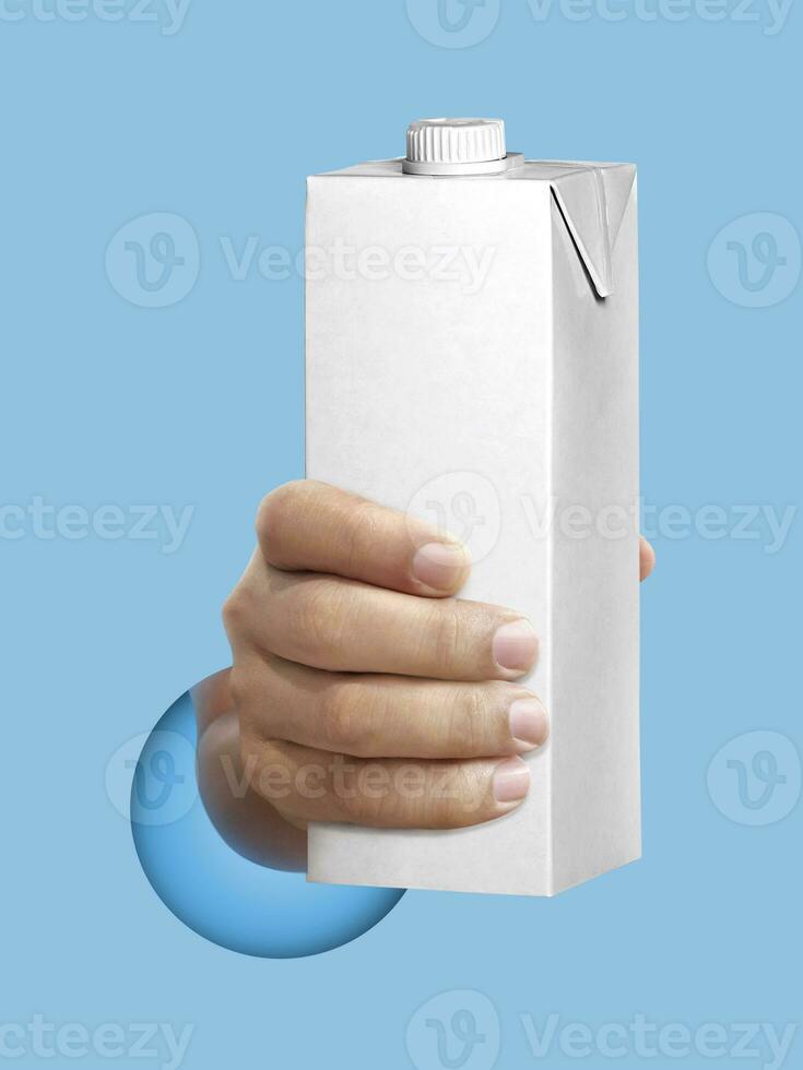 carton of milk or juice package in hand light blue background photo