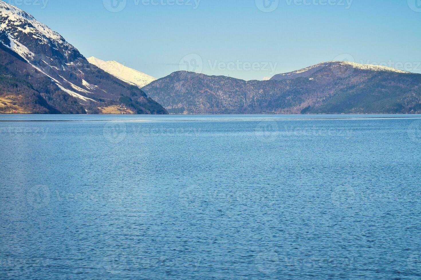 Fjord with snow covered mountains on the horizon. The water glistens in Norway photo