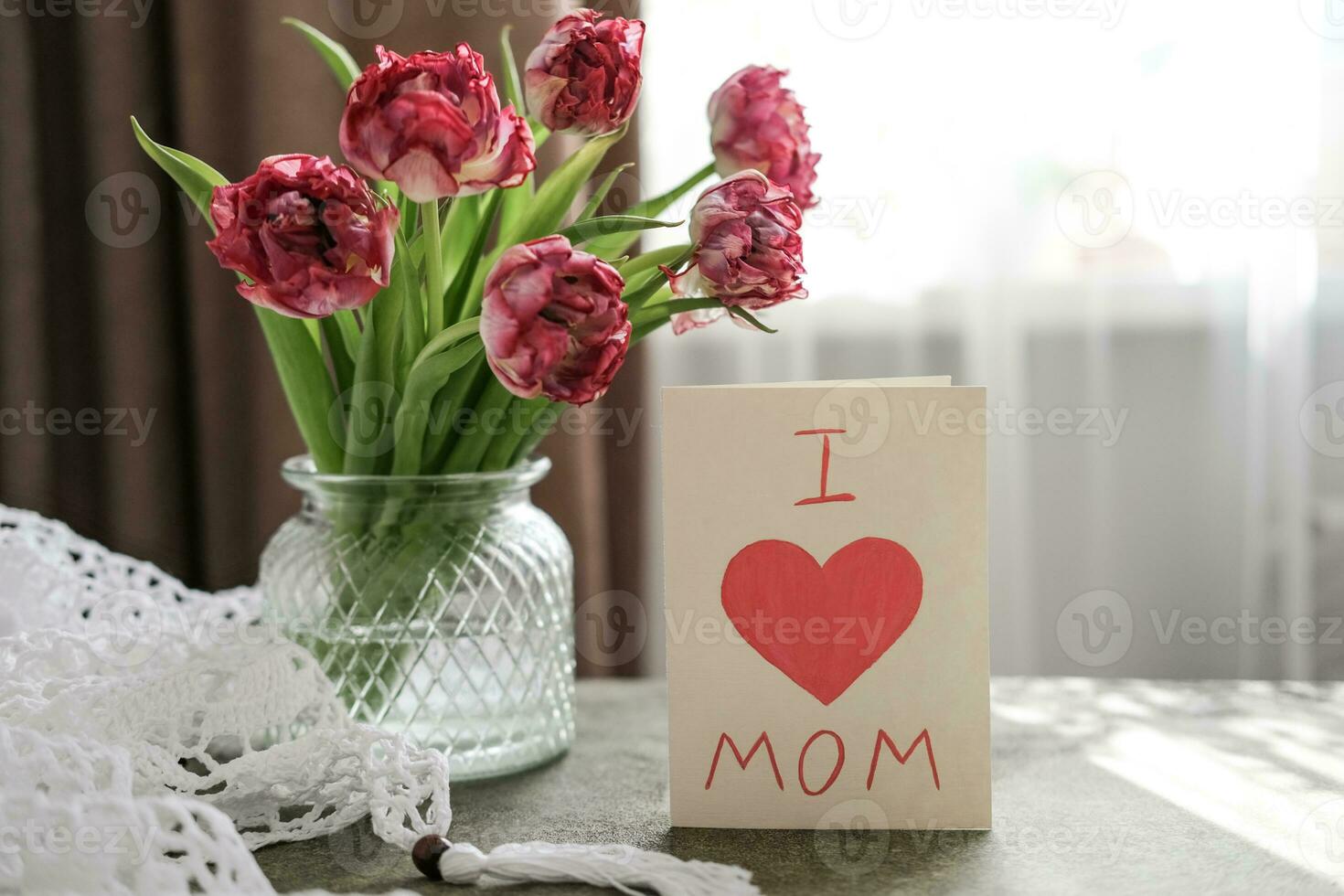 A bouquet of tulips in a vase and a card with the text I love mom. Mother's day concept photo