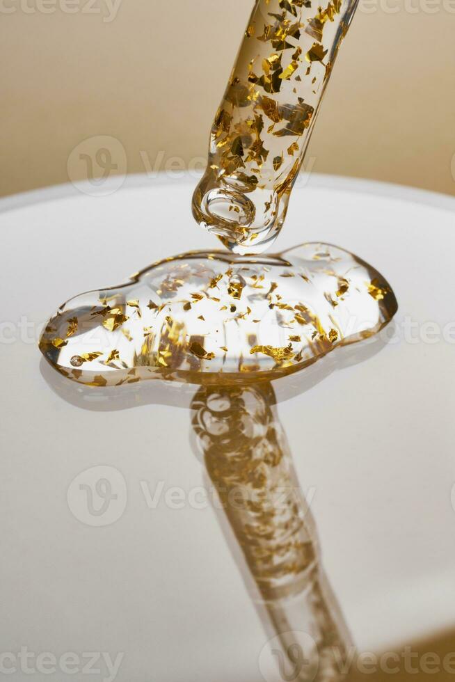 Pipette and gel cosmetic products with gold in a Petri dish on beige background photo