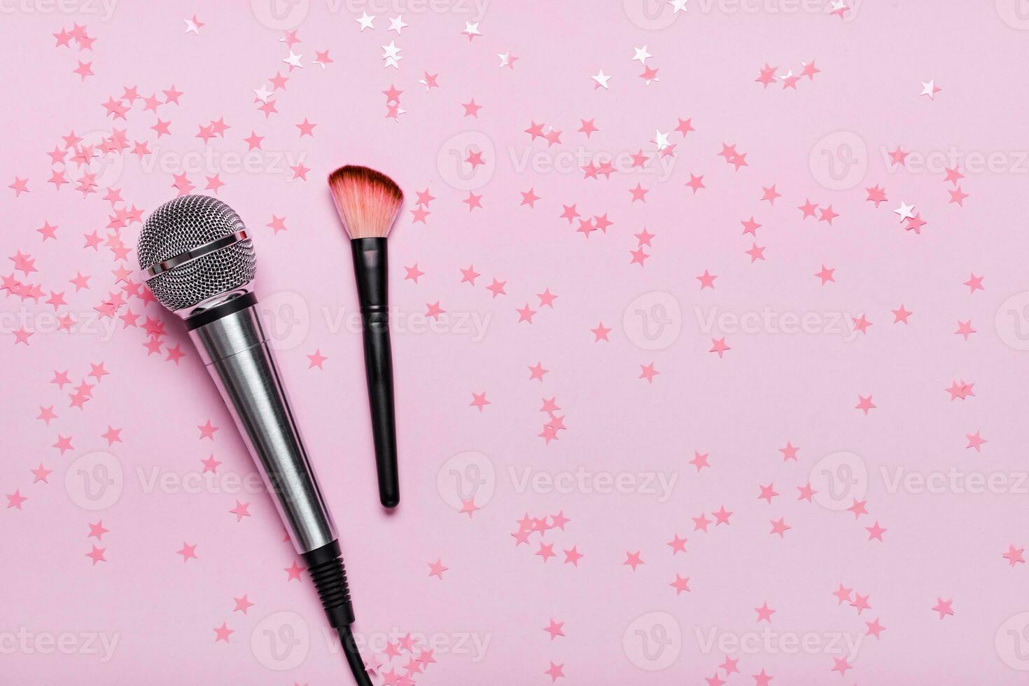 Microphone, confetti and brush on pink background. ASMR recording stress relieving sounds concept, flat lay photo