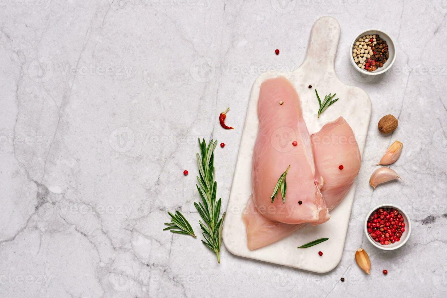 Fresh chicken breast fillet on cutting board with spices and herbs on gray marble background. Preparation for cooking. photo