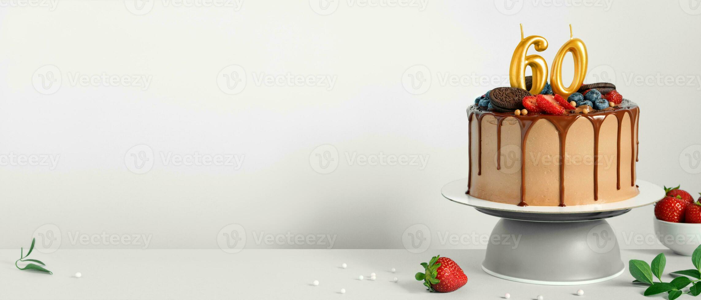 Banner with Chocolate birthday cake with berries, cookies and number sixty golden candles on White background, copy space photo