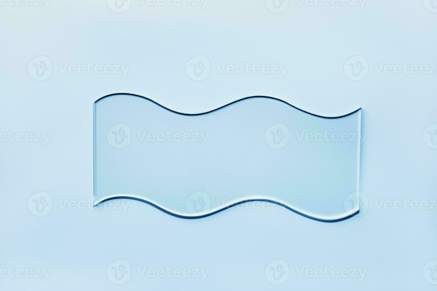 Empty glass wavy slide on blue background. Mockup for cosmetic or scientific product sample photo