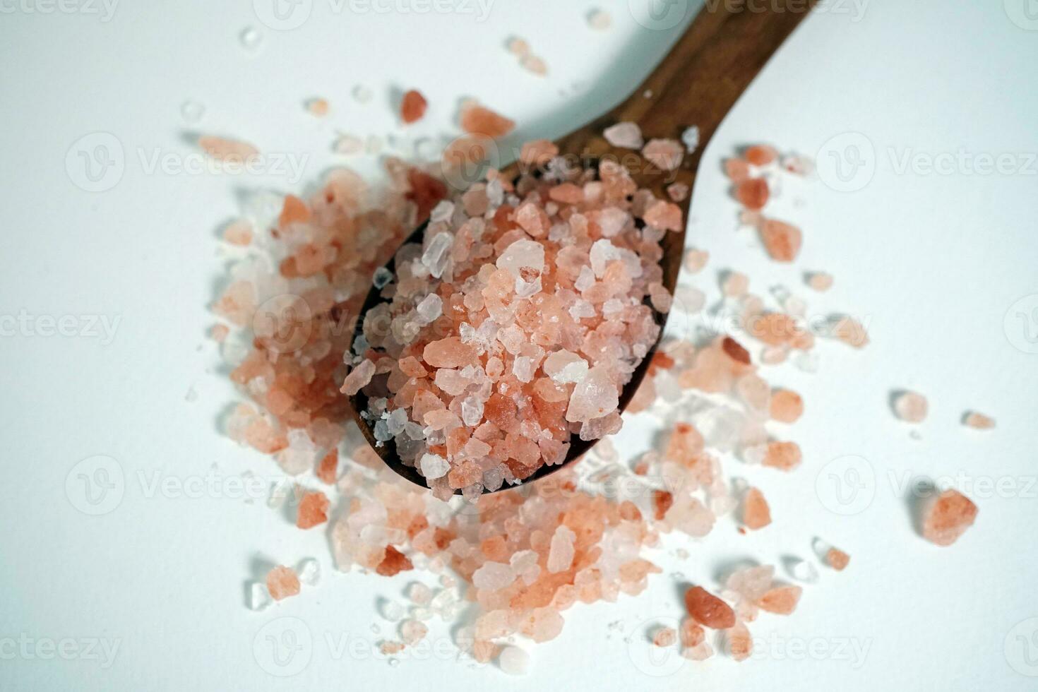 Himalayan pink salt crystals in a wooden spoon on white background. photo