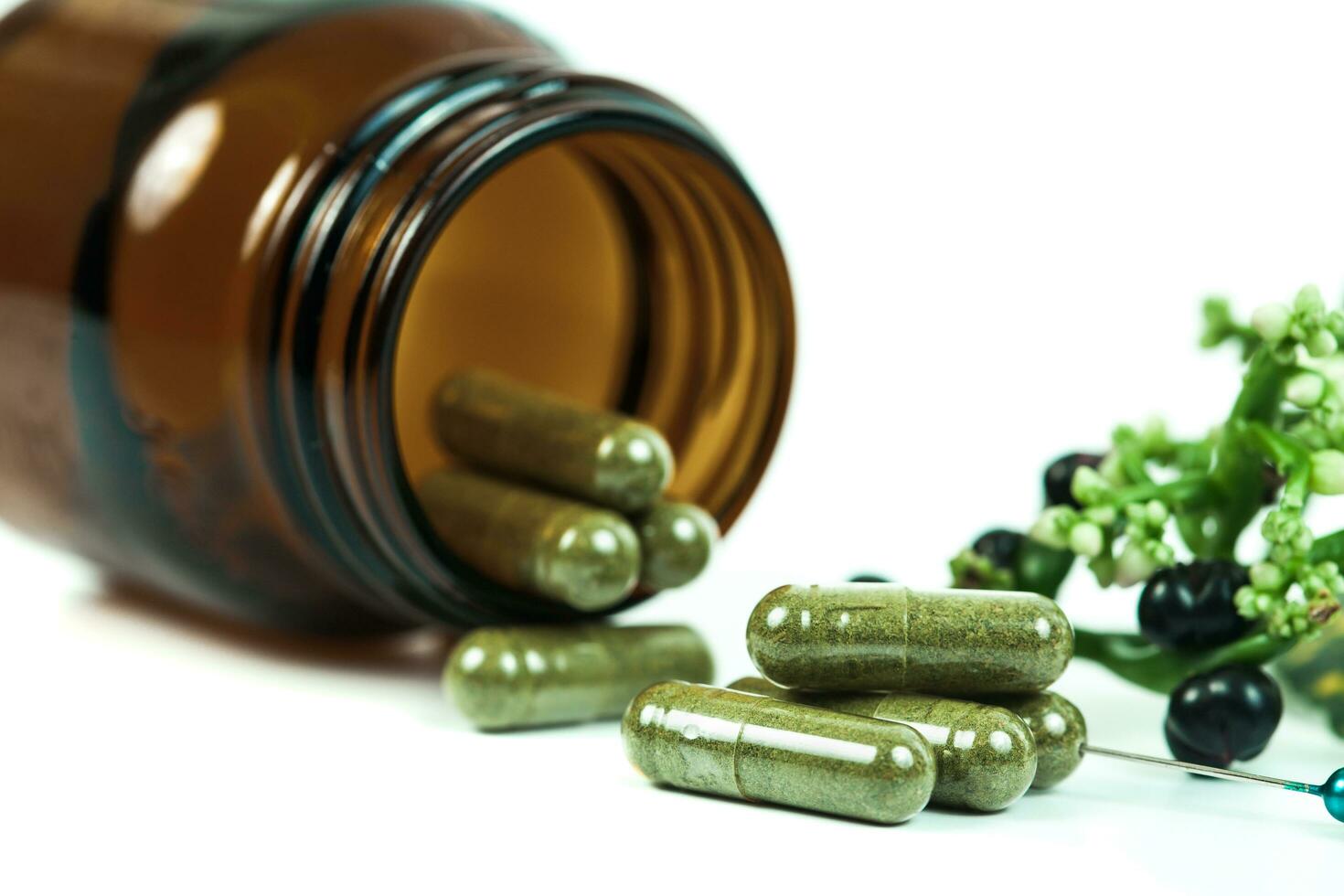 Herbal medicine capsules spilling out of a bottle on white photo