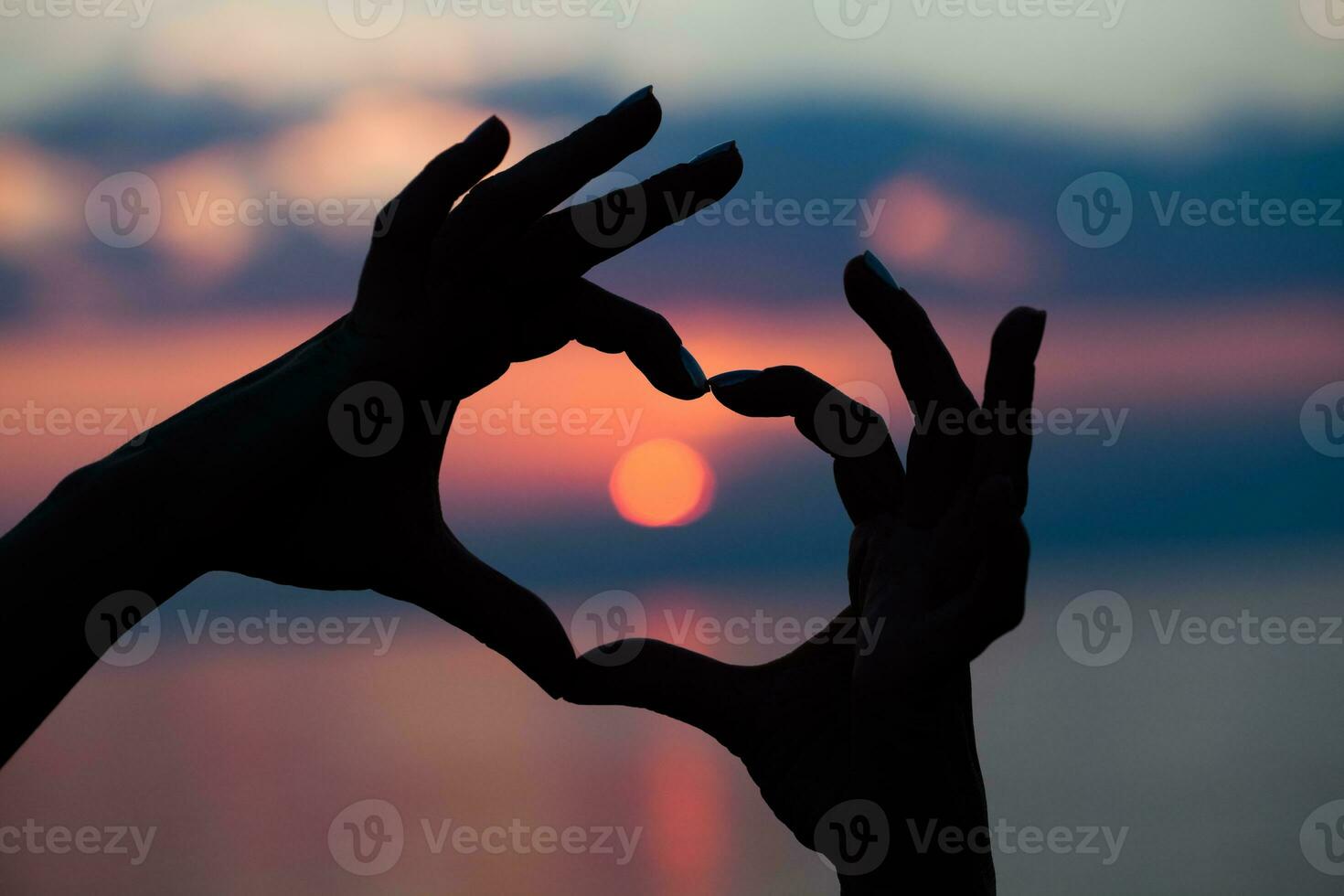 Hands with heart shape over the sunset photo