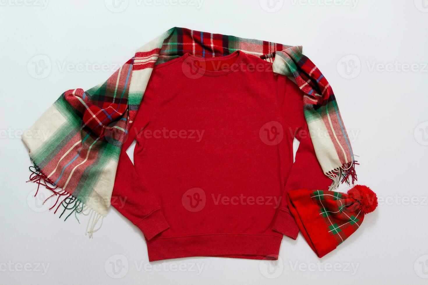 Close up red blank template sweatshirt with copy space and Christmas Holiday concept. Top view mockup hoodie and red holidays decorations on white background. Happy New Year accessories. Xmas outfit photo