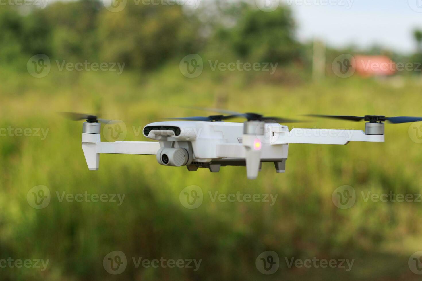 a photo of a drone flying with a blurry propeller against a green open space background. technology photo concept.