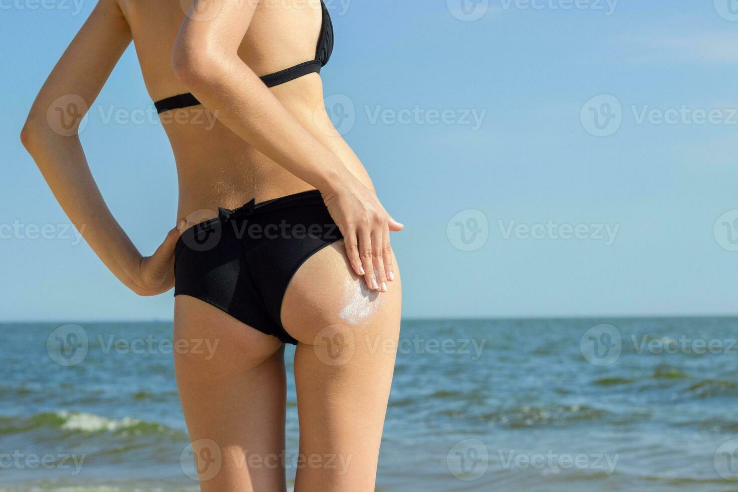 Suntan Lotion Woman Applying Sunscreen Solar Cream. Beautiful cute girl applying Sun Tan Cream on her skin on the beach. Sun Tanning. Skin care and Protection. Vacation photo