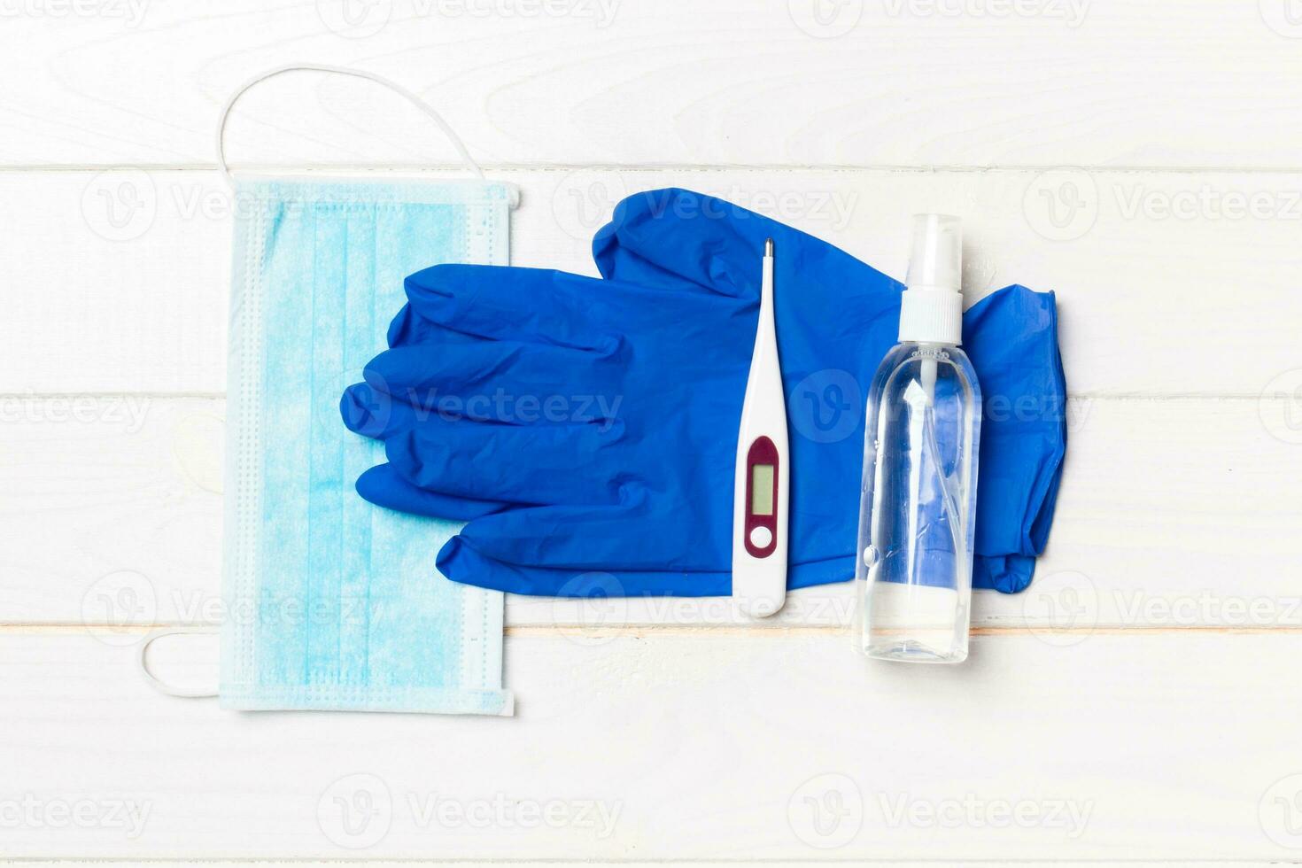 Top view of latex gloves, bottle of alcohol hand sanitizes, medical mask and digital thermometer on wooden background. Antibacterial virus protection concept with copy space photo