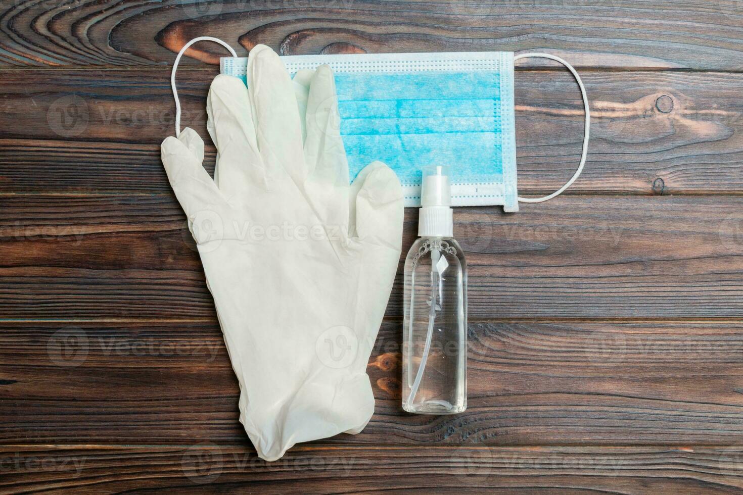 Top view of protective medical equipment such as surgical mask, hand alcohol sanitizer and latex gloves on wooden background. Health care concept with copy space photo