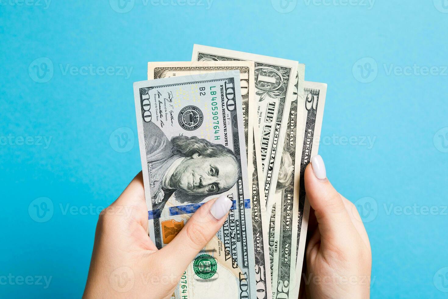 Top view of female hand holding a pack of various dollar bills on colorful background. Wage and salary concept photo