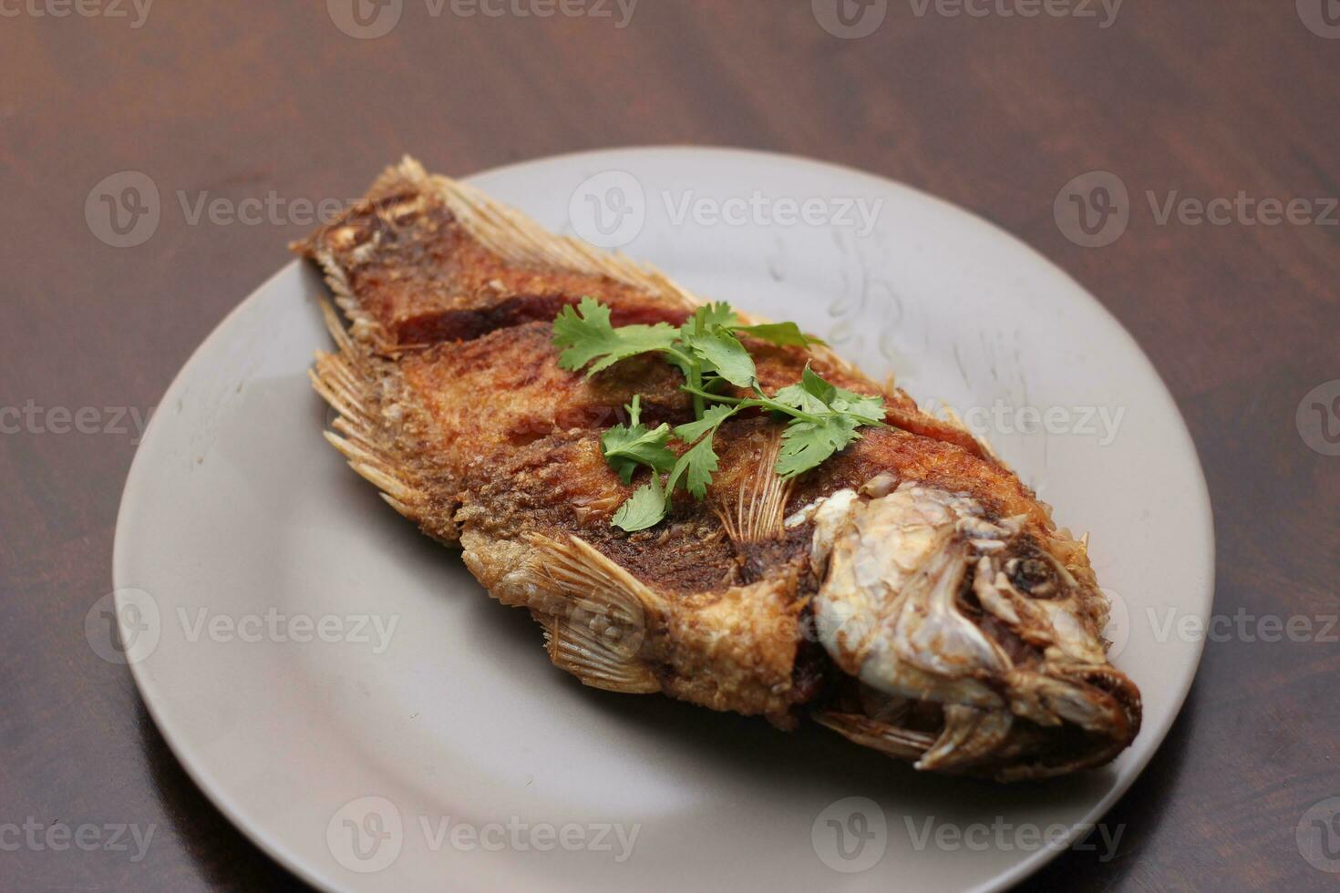 The fried tilapia was just right. Served in gray work on a brown wooden table. photo