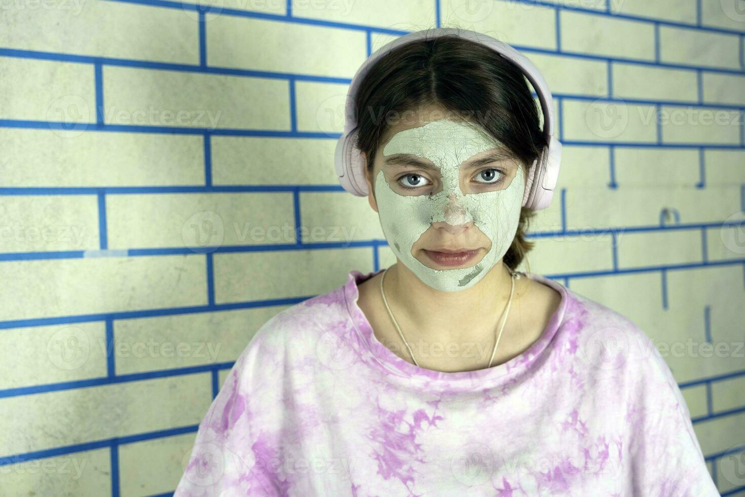 teenage girl takes care of her face by applying a cosmetic mask photo