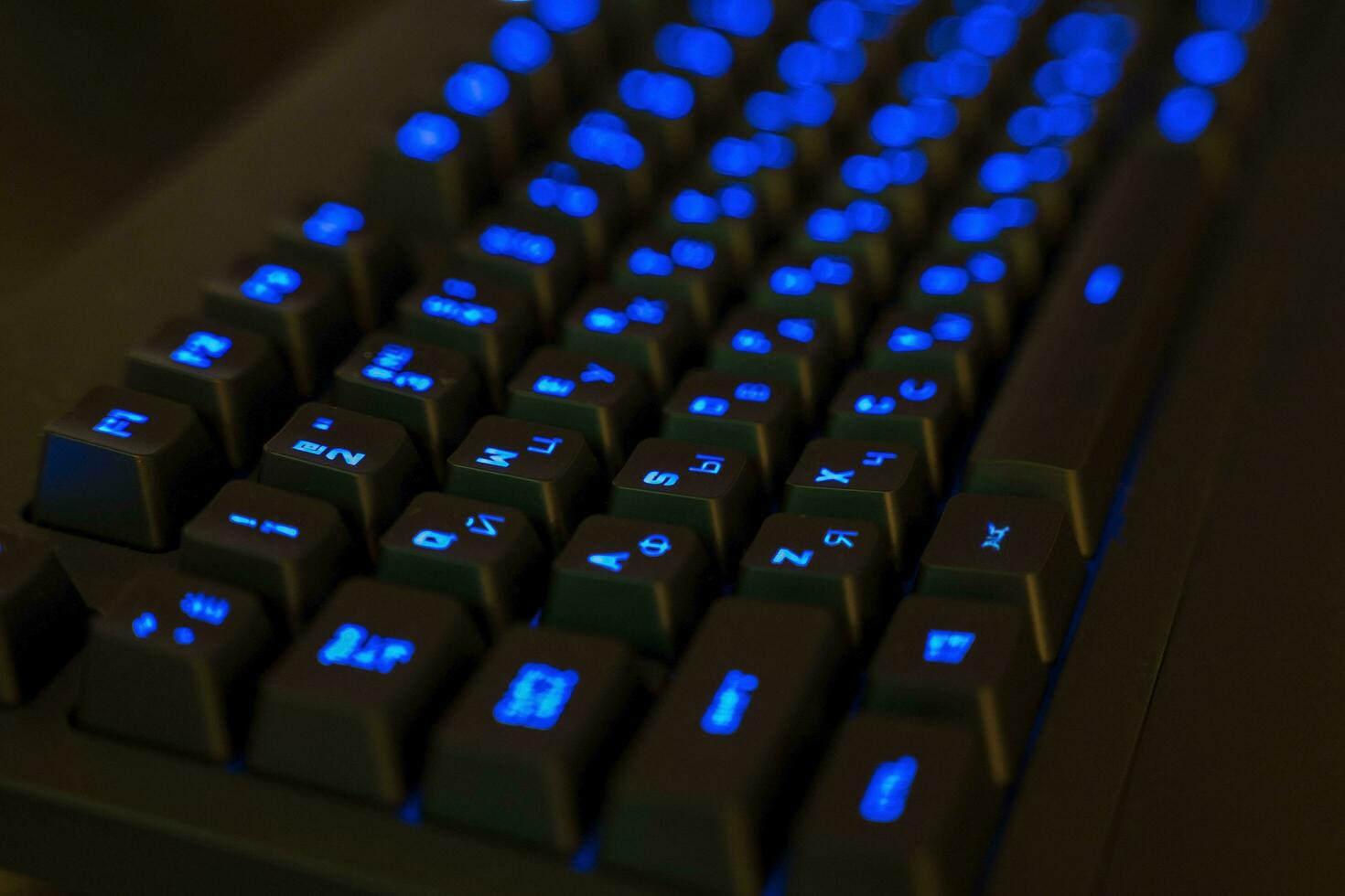 Gaming Keyboard with Illuminated Keys. black keys with blue glowing letters photo