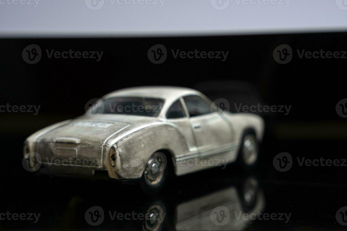 a model of an old classic shabby car on glossy black glass. close-up photo