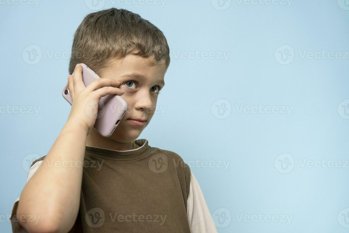 travieso caucásico chico hablando en el teléfono . un encantador niño con un teléfono foto