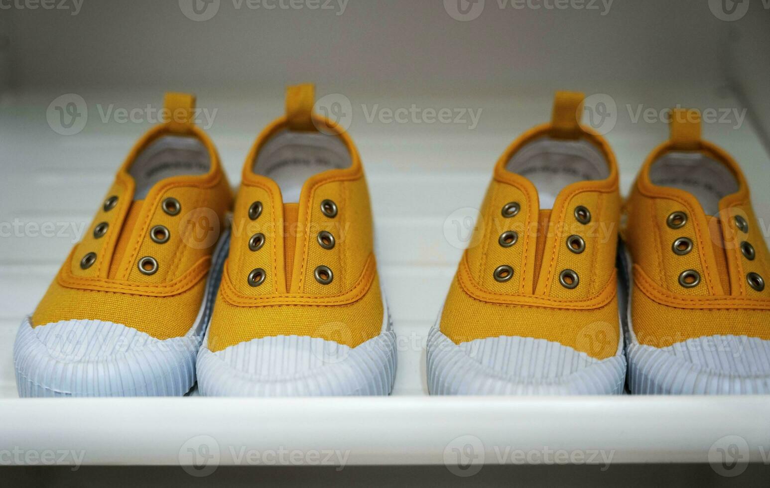 children's red rubber fashionable sneakers stand in a row on the shelf photo